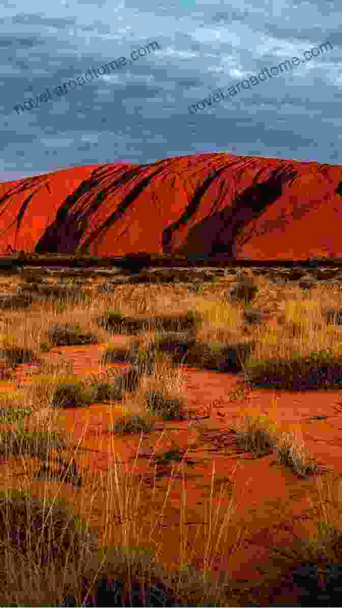 A Vibrant Sunset Casts A Warm Glow On The Silhouette Of Uluru, Its Towering Presence Dominating The Vast Outback Landscape. FINDING ULURU Raymond Barfield